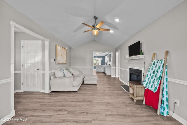 living room with light hardwood / wood-style floors, ceiling fan, and lofted ceiling