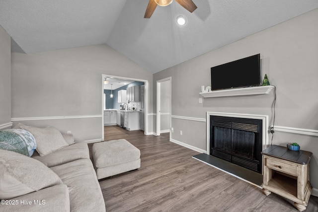 living room with a textured ceiling, ceiling fan, wood-type flooring, and vaulted ceiling