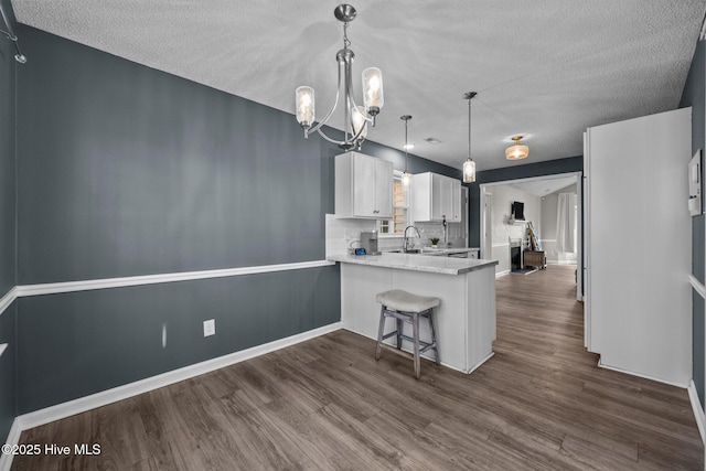 kitchen featuring white cabinets, dark hardwood / wood-style floors, a kitchen bar, and kitchen peninsula