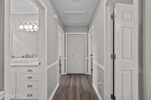 hall with sink, dark wood-type flooring, and a textured ceiling