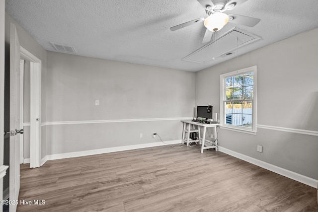 unfurnished office featuring ceiling fan, hardwood / wood-style floors, and a textured ceiling