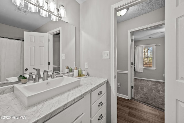 bathroom with hardwood / wood-style floors, vanity, and a textured ceiling