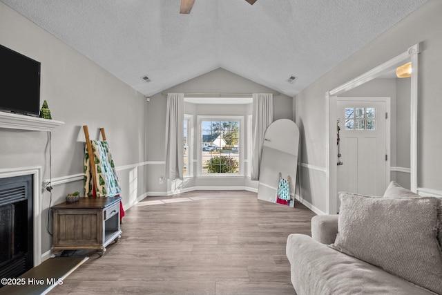 living room featuring hardwood / wood-style floors, a textured ceiling, ceiling fan, and lofted ceiling