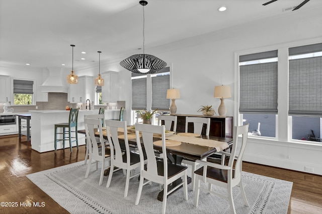 dining room featuring crown molding, dark hardwood / wood-style flooring, and sink