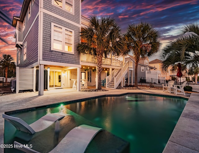 pool at dusk with central air condition unit and a patio