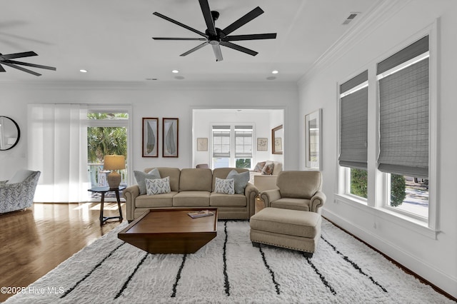 living room with hardwood / wood-style flooring, a wealth of natural light, and ornamental molding