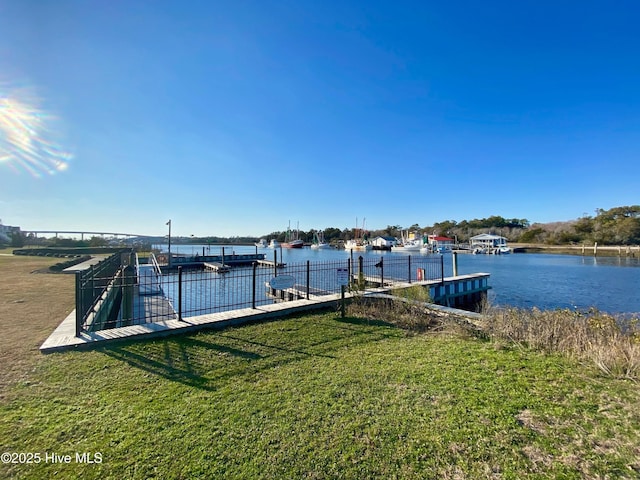 view of dock with a yard and a water view