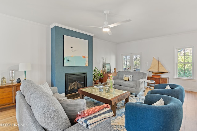 living room with a large fireplace, ornamental molding, and light hardwood / wood-style floors