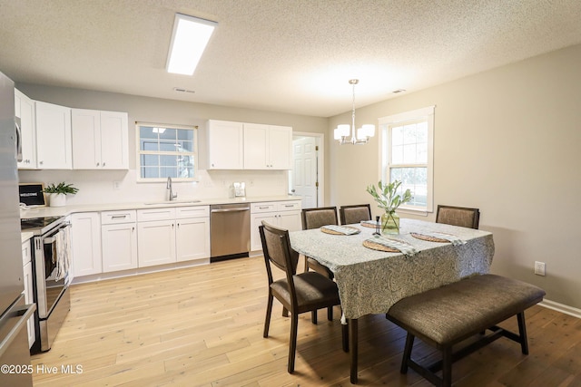 dining area featuring a textured ceiling, a notable chandelier, sink, and light hardwood / wood-style flooring