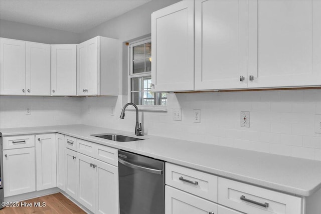 kitchen with dishwasher, backsplash, white cabinetry, and sink