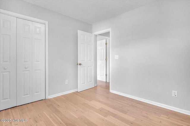 unfurnished bedroom with a textured ceiling, light hardwood / wood-style floors, and a closet