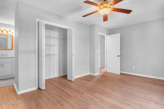 unfurnished bedroom featuring ceiling fan, sink, light hardwood / wood-style flooring, ensuite bathroom, and a textured ceiling