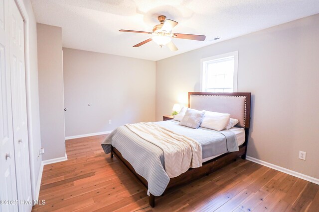 bedroom featuring ceiling fan, dark hardwood / wood-style flooring, a textured ceiling, and a closet