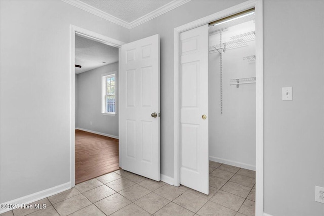 unfurnished bedroom with ornamental molding, light tile patterned floors, a textured ceiling, and a closet