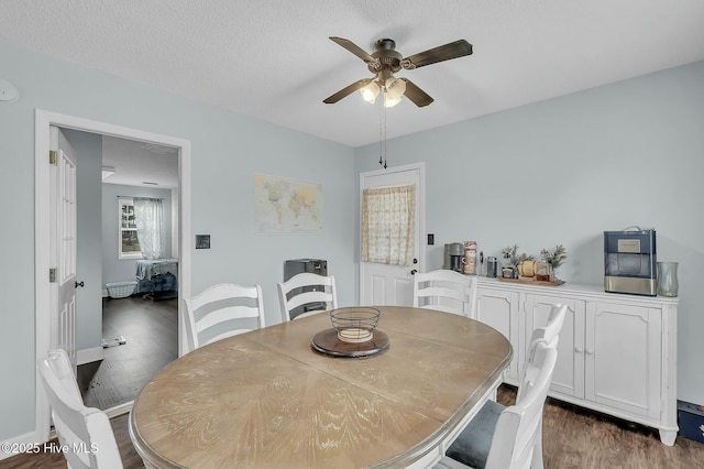 dining area with ceiling fan, dark hardwood / wood-style flooring, and a textured ceiling