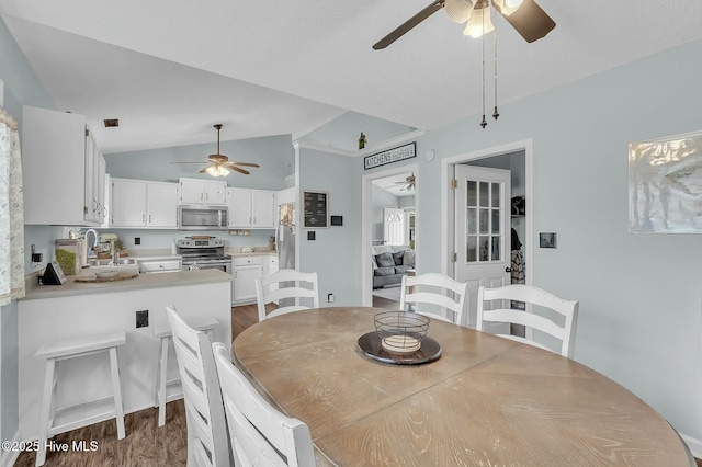 dining room featuring ceiling fan, dark hardwood / wood-style flooring, lofted ceiling, and sink