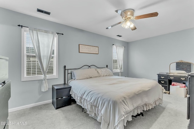 bedroom with multiple windows, ceiling fan, and light colored carpet