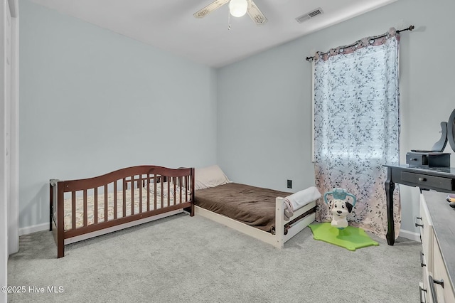 carpeted bedroom with a nursery area and ceiling fan