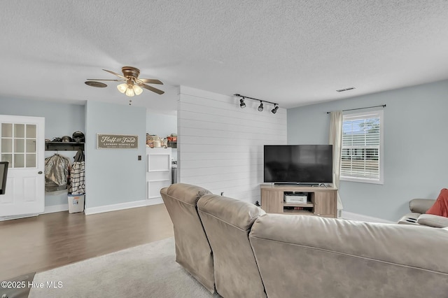 living room with rail lighting, ceiling fan, and a textured ceiling