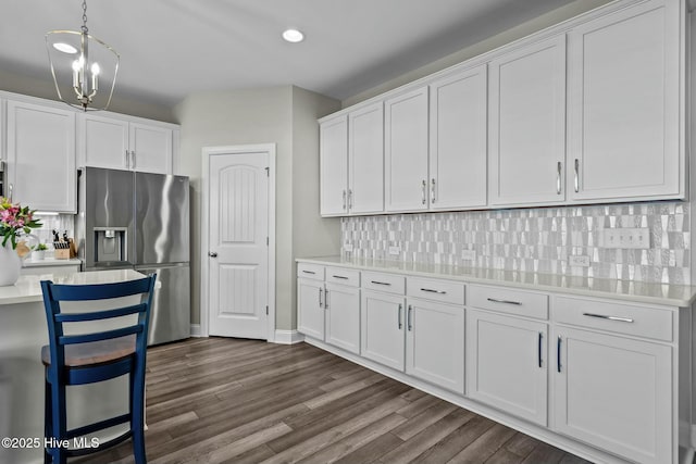 kitchen featuring decorative backsplash, stainless steel fridge with ice dispenser, white cabinets, and decorative light fixtures