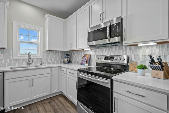 kitchen featuring backsplash, sink, dark hardwood / wood-style floors, white cabinetry, and stainless steel appliances