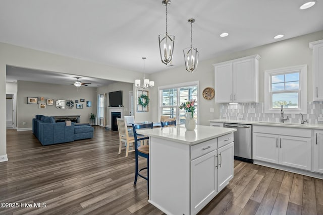 kitchen featuring pendant lighting, a center island, white cabinets, sink, and stainless steel dishwasher