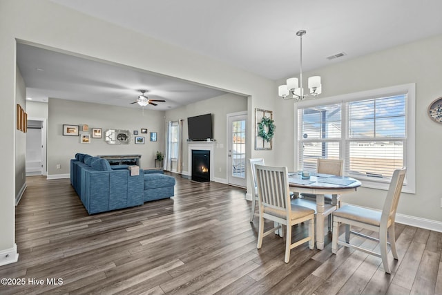 dining space with ceiling fan with notable chandelier and dark wood-type flooring