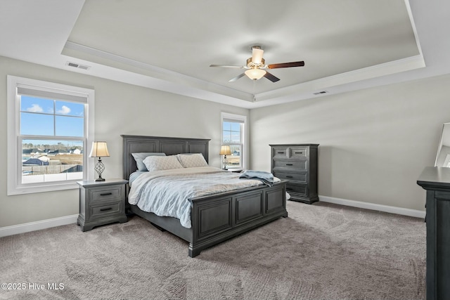 carpeted bedroom featuring a tray ceiling and ceiling fan