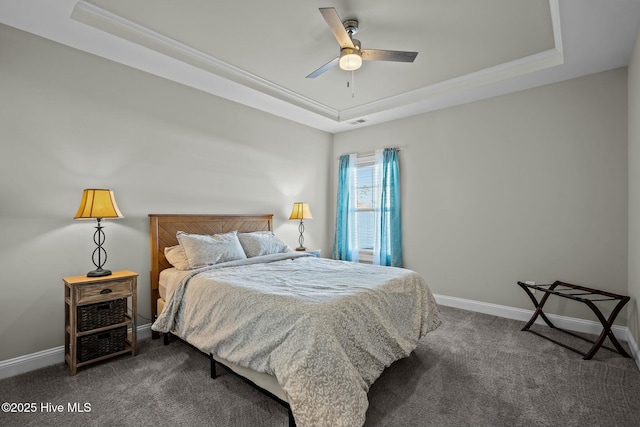 bedroom featuring a raised ceiling, ceiling fan, and dark carpet