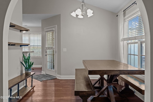 dining room featuring dark wood-type flooring, a healthy amount of sunlight, and an inviting chandelier