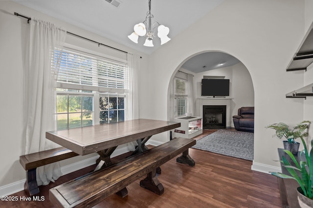 dining room with dark hardwood / wood-style flooring, lofted ceiling, and a notable chandelier