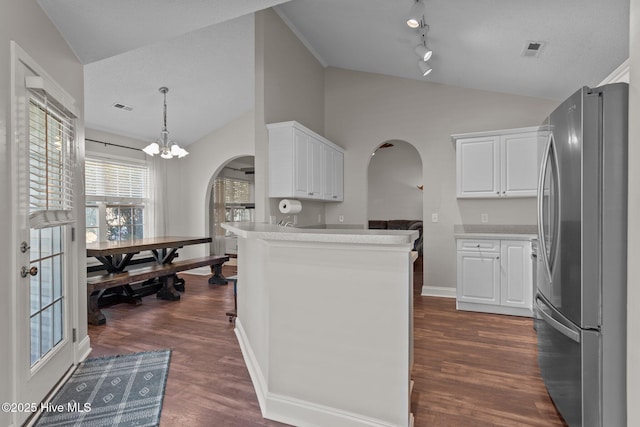 kitchen with white cabinets, kitchen peninsula, dark wood-type flooring, and stainless steel refrigerator