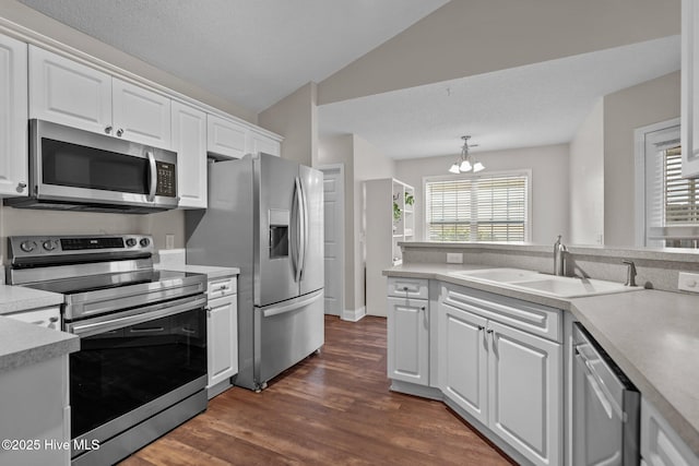 kitchen featuring appliances with stainless steel finishes, vaulted ceiling, decorative light fixtures, a notable chandelier, and white cabinets