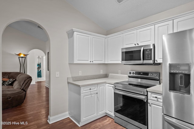 kitchen with white cabinets, dark hardwood / wood-style flooring, lofted ceiling, and appliances with stainless steel finishes