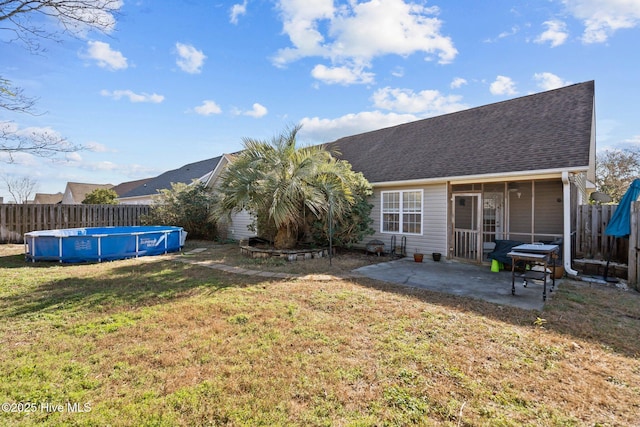 rear view of house with a patio, a fenced in pool, a lawn, and a sunroom