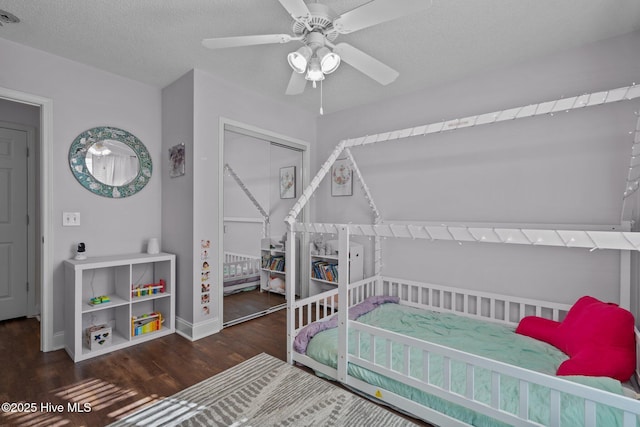 bedroom with ceiling fan, dark hardwood / wood-style flooring, a textured ceiling, and a closet