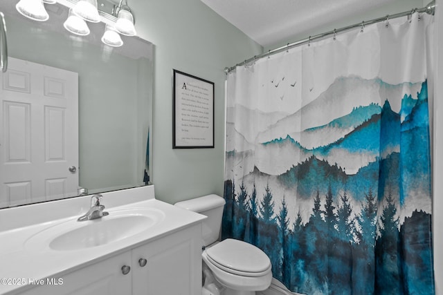 bathroom with vanity, curtained shower, toilet, and a textured ceiling