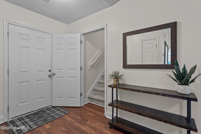 foyer entrance with a textured ceiling and dark wood-type flooring