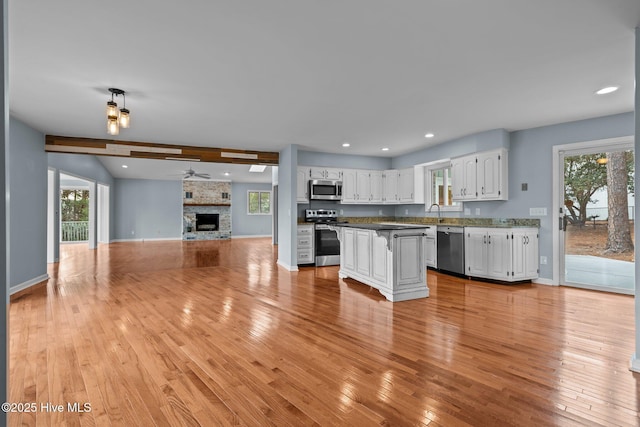 kitchen with ceiling fan, light wood-type flooring, a fireplace, white cabinetry, and stainless steel appliances