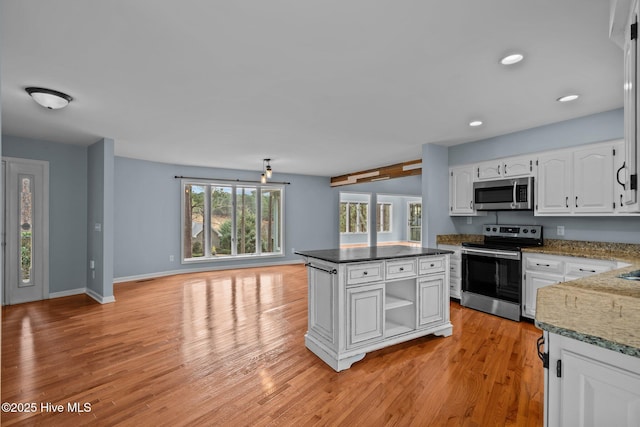 kitchen featuring a center island, white cabinets, dark stone countertops, light wood-type flooring, and appliances with stainless steel finishes