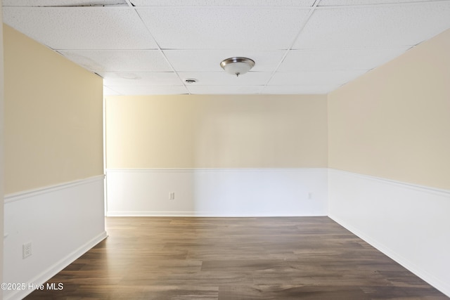 spare room with a paneled ceiling and dark hardwood / wood-style floors