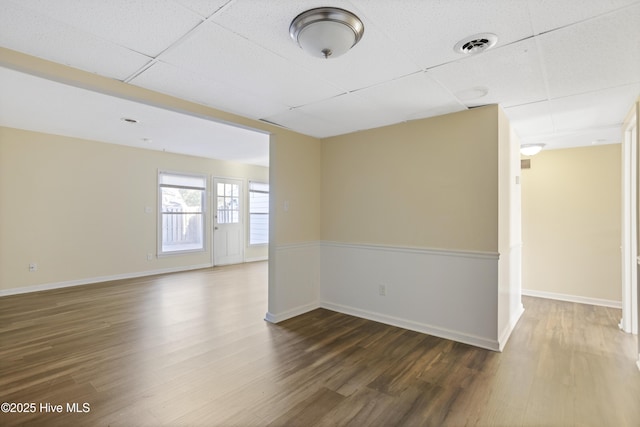 spare room with dark hardwood / wood-style floors and a drop ceiling