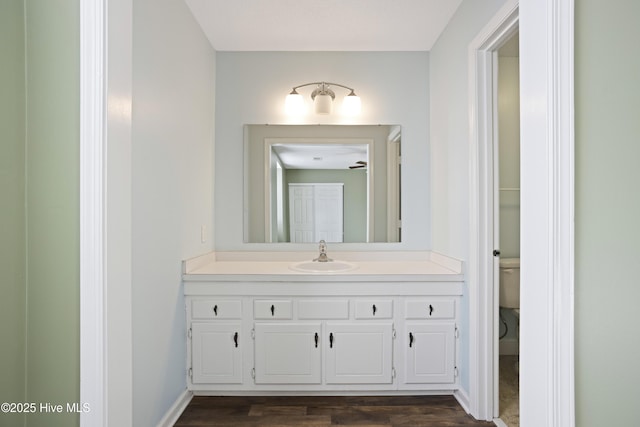 bathroom featuring toilet, vanity, wood-type flooring, and ceiling fan