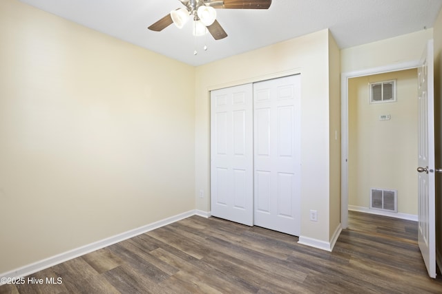 unfurnished bedroom featuring ceiling fan, a closet, and dark wood-type flooring