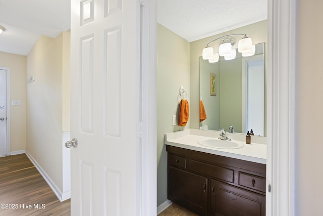 bathroom with hardwood / wood-style flooring, a textured ceiling, and vanity