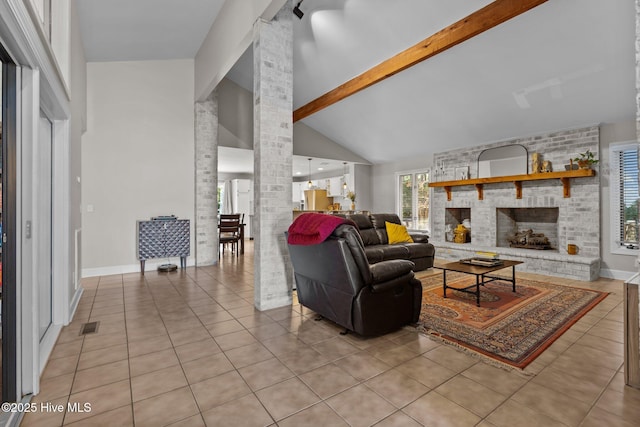 living room with high vaulted ceiling, a brick fireplace, light tile patterned floors, ornate columns, and beam ceiling