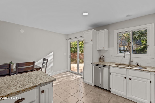 kitchen featuring dishwasher, white cabinets, sink, a wealth of natural light, and light stone counters