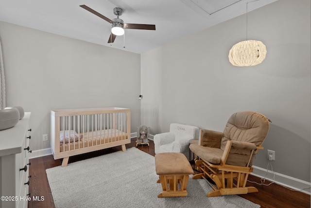 bedroom with dark hardwood / wood-style floors, ceiling fan, and a crib