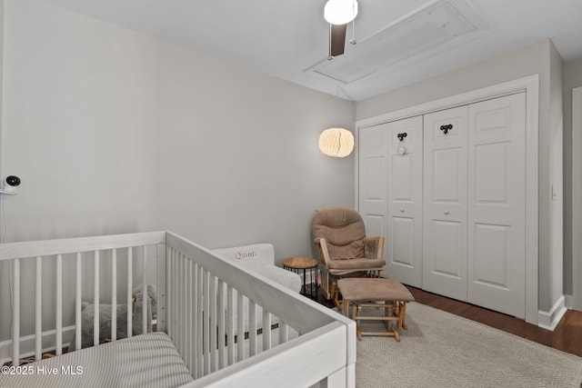 bedroom featuring dark hardwood / wood-style flooring, a nursery area, a closet, and ceiling fan