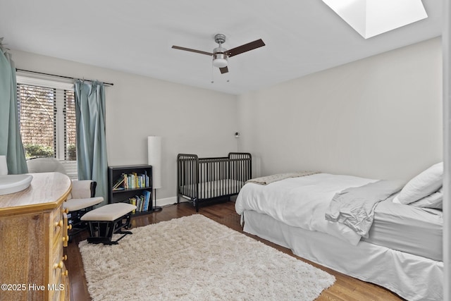 bedroom featuring a skylight, ceiling fan, and dark hardwood / wood-style flooring